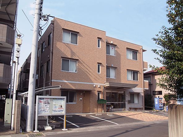 ２つの建物の間に建つ、手前に駐輪場や２台分の駐車場がある施設