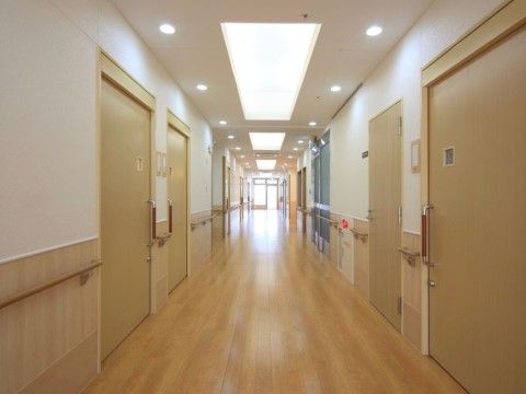 通路の壁には手すりが備え付けられており、火災報知器設備がある。前方には窓があり、光が差し込んできて明るい。