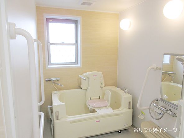 出入口のドアは大きな白い引き戸になっている。浴室には寝たままの姿勢で入浴できる介護浴槽が置かれている。
