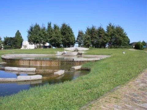 池のまわりが芝生になっていて、その側の歩道はレンガ風の道になっている。奥には木々が植えられており、自然を感じられる公園である。