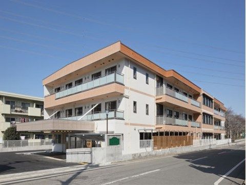玄関前に屋根が張り出した、白と茶色の３階建ての建物