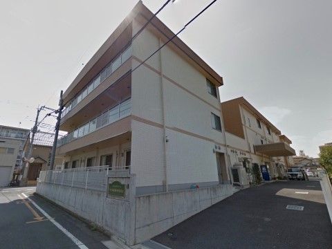 ３階建ての街の景観になじむデザインの建物である。門付近には本施設名を標記したプレートを設置している。