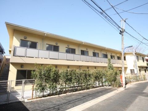外階段がついており、同じ形の窓が並ぶ2階建てのクリーム色の建物