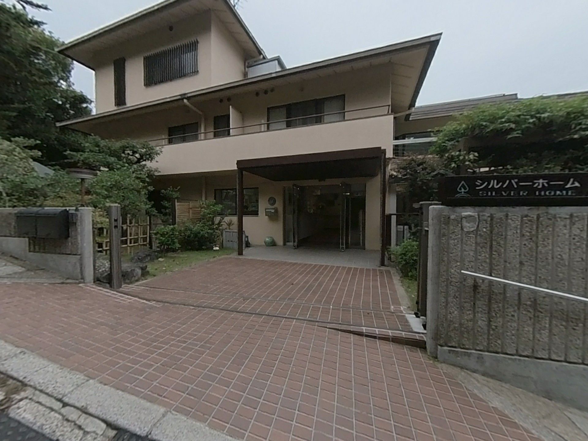 坂の途中に建つ、勾配のついた屋根を持つ施設の玄関側部分