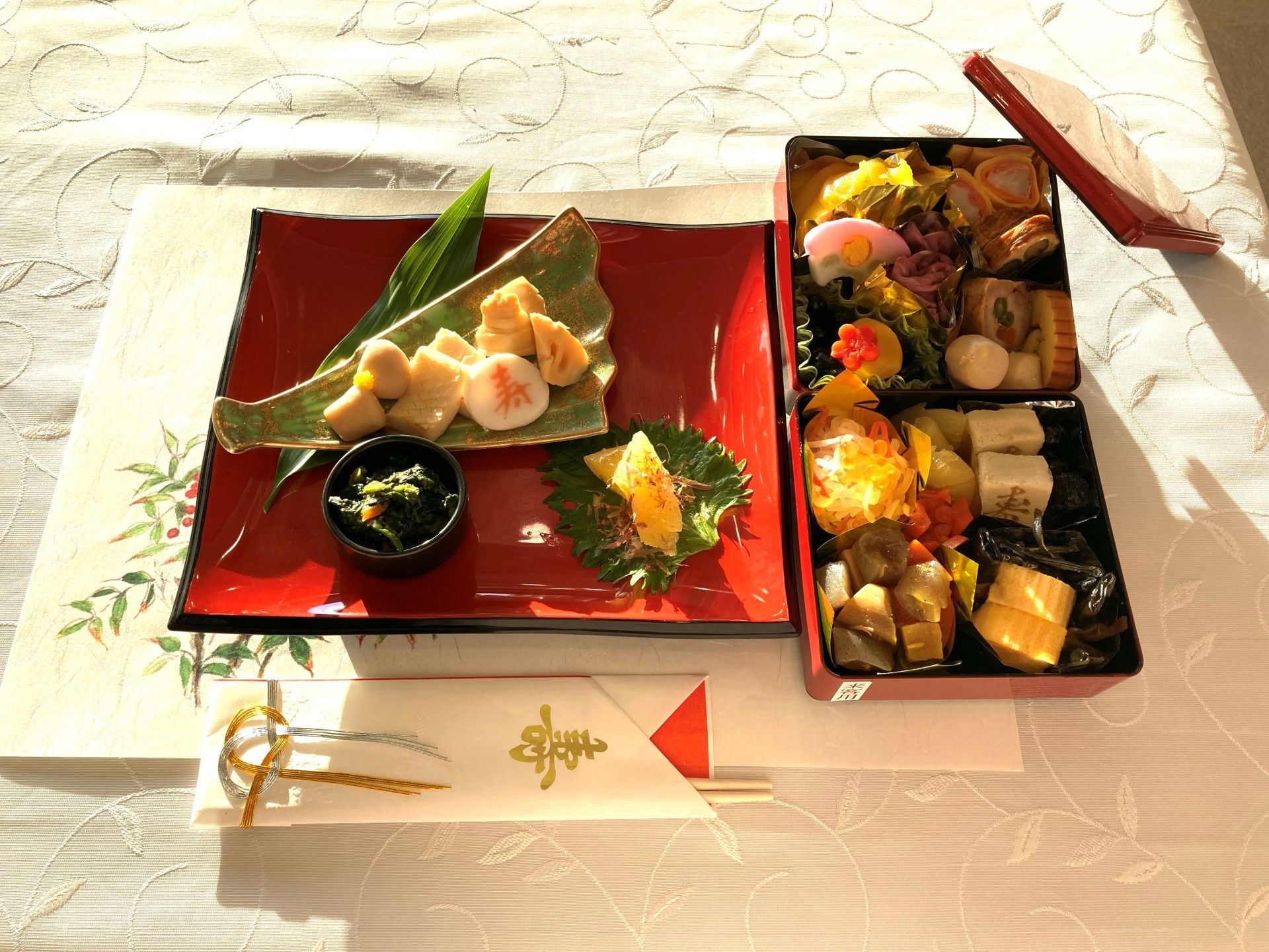赤い半月盆の上に並ぶ5品の料理に、添えられた箸と漆塗りのようなスプーン