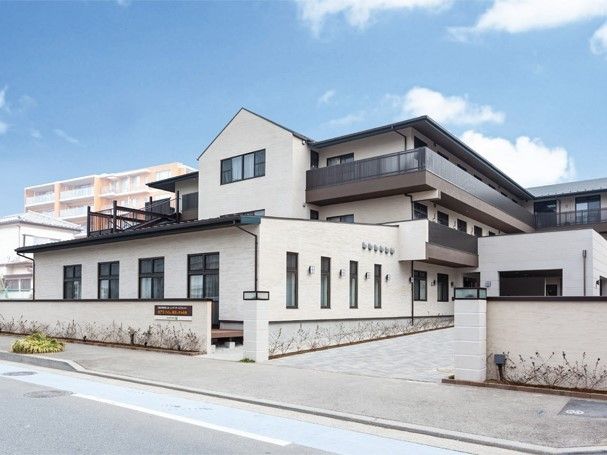 濃い色の屋根に白っぽい壁の、床面積がかなり広い印象の建物