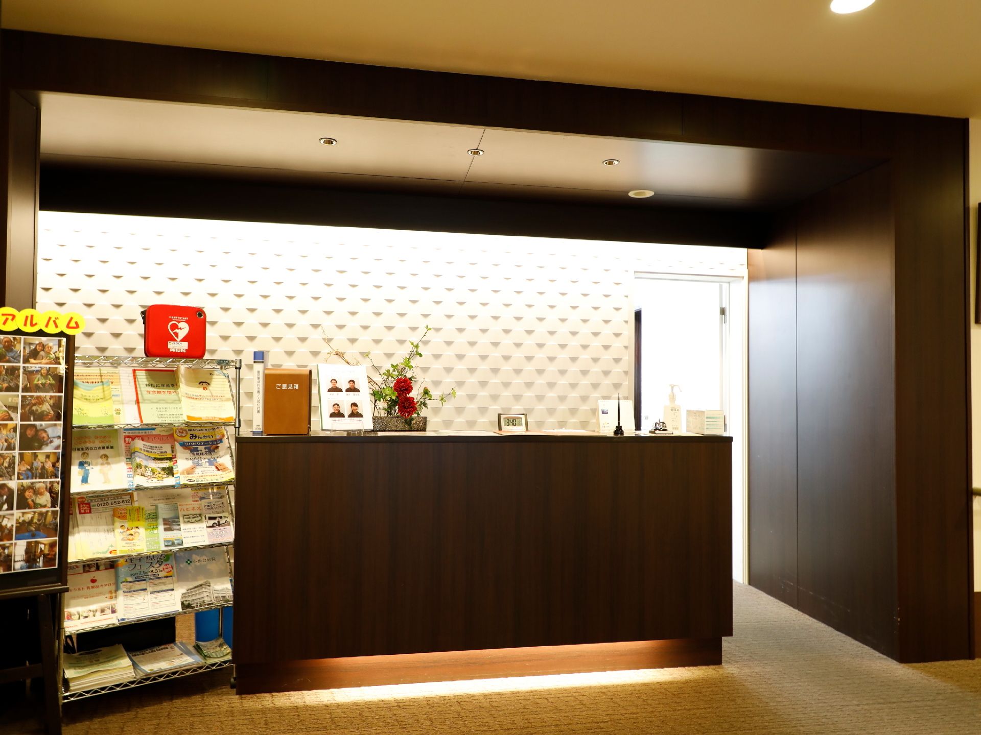 施設の入口には受付がある。カウンターの上には花が飾られていて、その横にはスタッフの写真も置いてある。