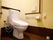 トイレの壁には手すりが縦方向、横方向に設置されている。温水洗浄便座、緊急時のナースコールが完備されている。