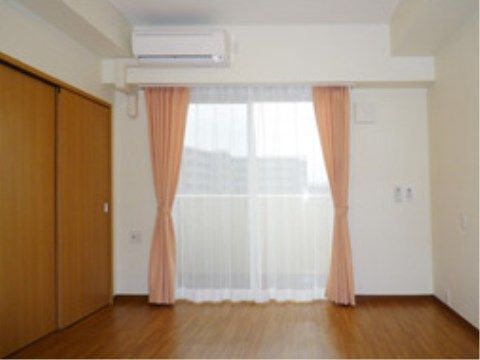 居室にはカーテンがかけられた窓がある。部屋の窓からは外の景色を眺めることができる。ベランダには柵が設置されている。