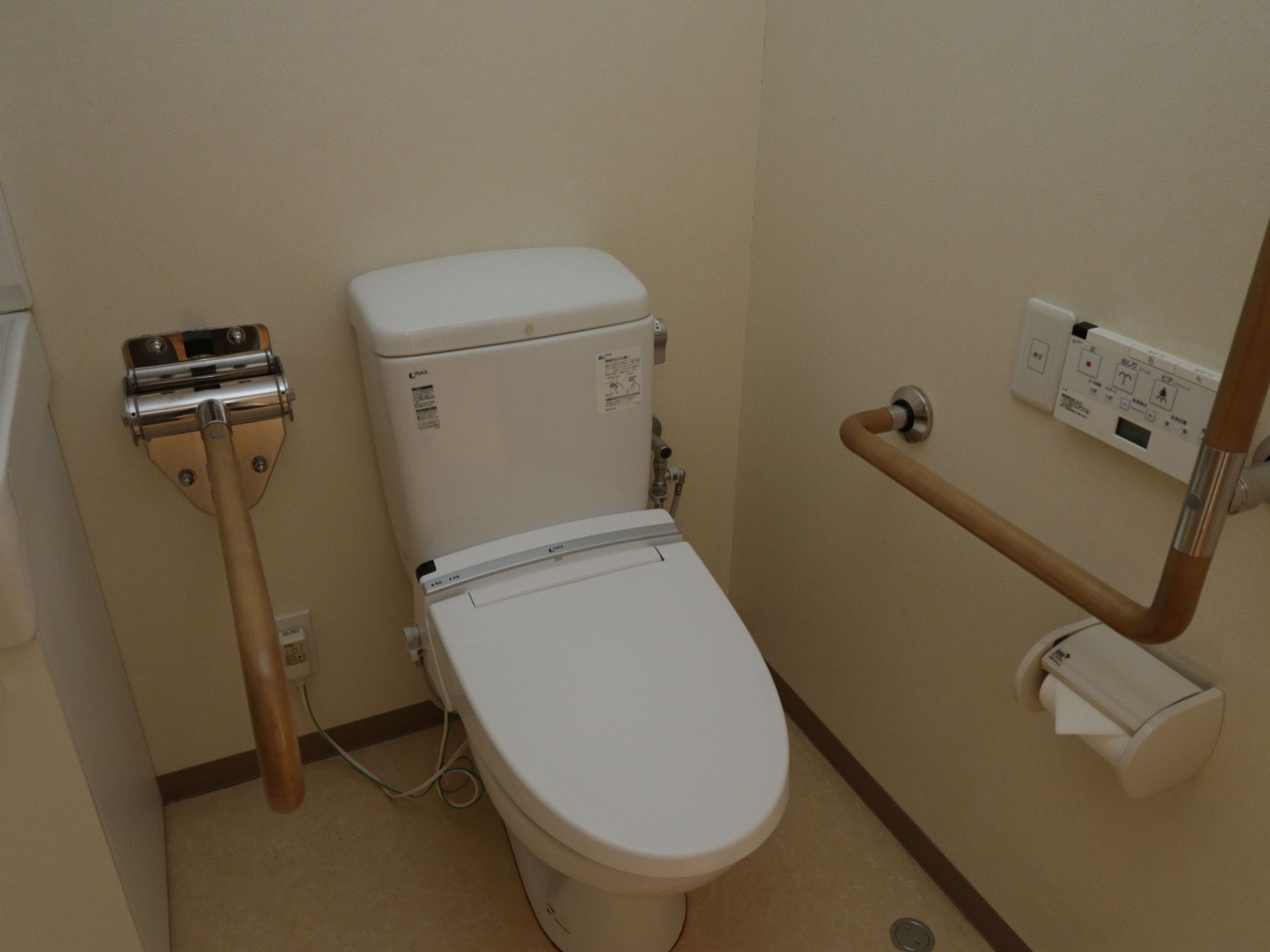トイレに温水洗浄便座を取りつけている。操作は壁のパネルで行う。壁には固定式のものと、可動式の手すりがある。