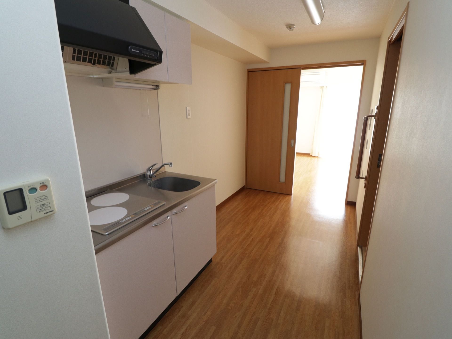 居室に入ると左手の壁に設備のスイッチがある。その奥にキッチンがあり、居住スペースの扉までの間に家財道具を置く場所がある。