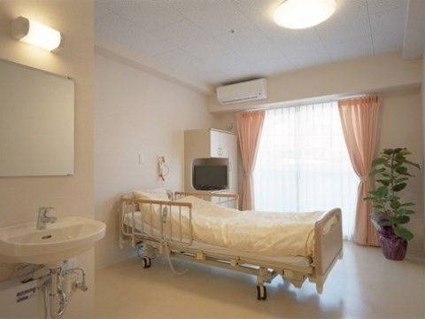 手前に洗面台、中央にベッド、奥に窓がある、床も壁も白い個室