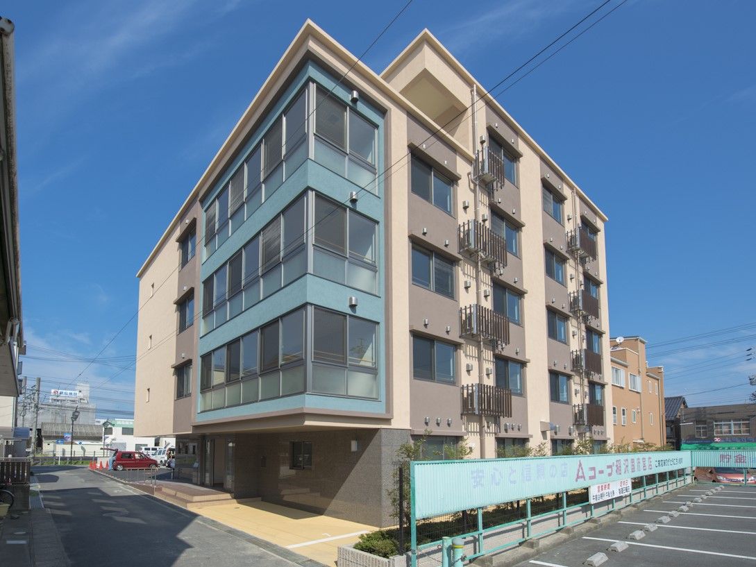 施設の外には、道路側に手すりが設けられている。外壁は、薄い茶色と、窓の周りの濃い茶色との2色を用いたデザインである。
