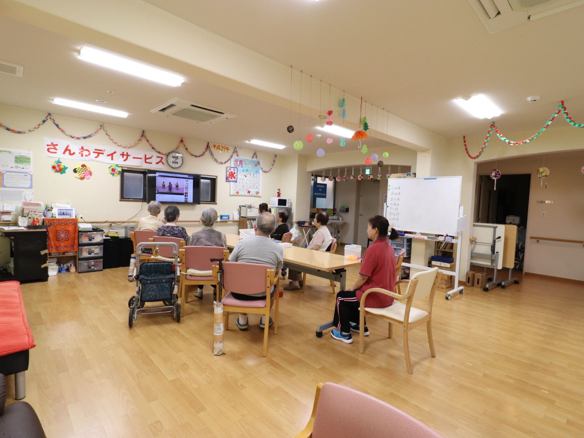 壁際には、プラスティック製の収納ボックスや木製のボックスが置いてあるのが見える。天板の上に細々とものがおいてある。壁には時計がかけてある。