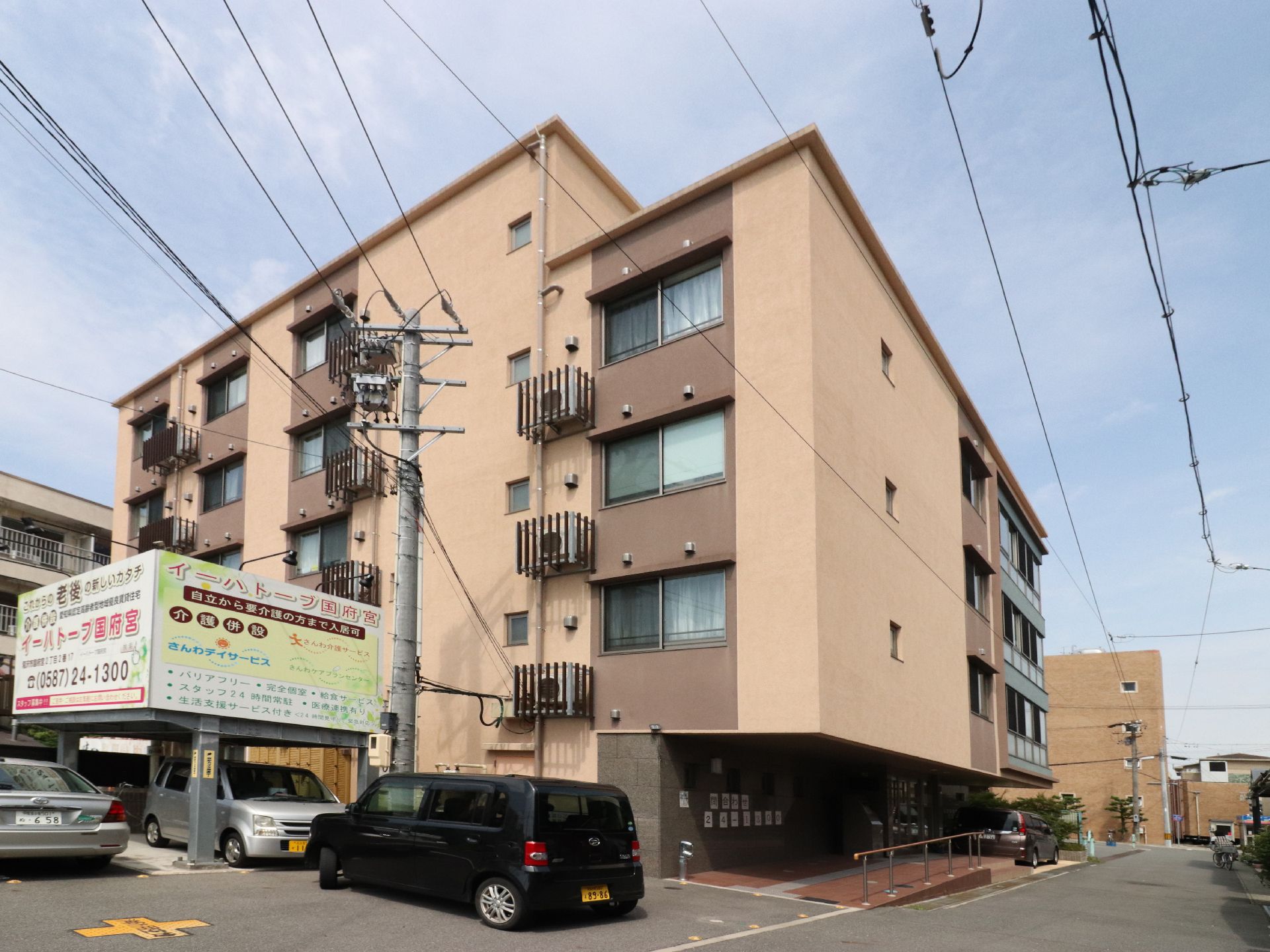 駐車場が併設した建物と、その横に設置された施設の説明が書かれた看板