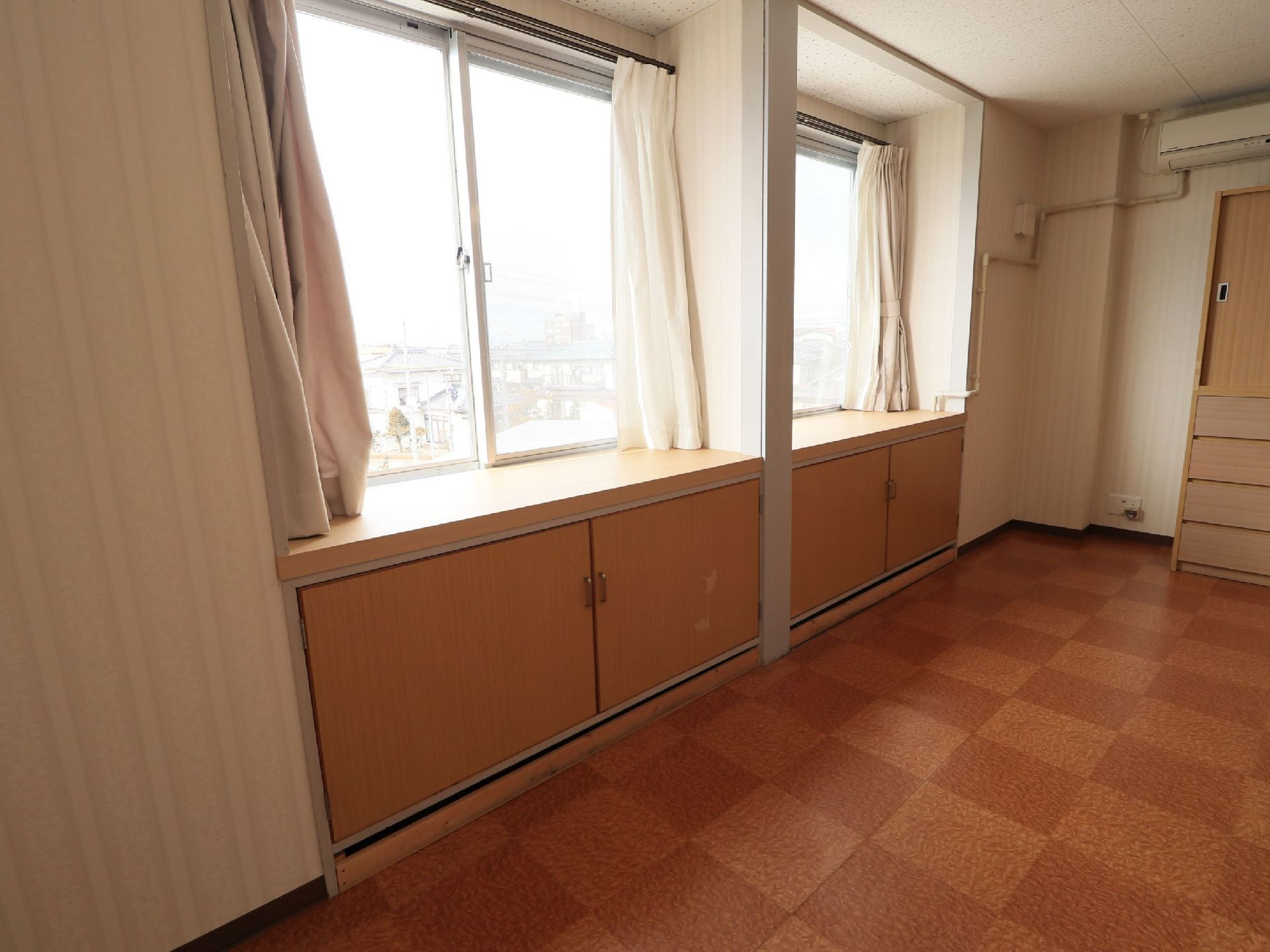 居室には窓があり、カーテンが掛けられている。窓の下はカウンターになっていて、下に収納スペースが設置されている。