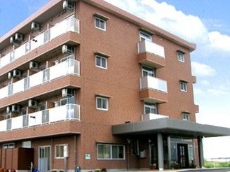 赤茶色の見た目が特徴的で、玄関に大きな庇がある建物