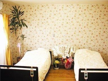 花と観葉植物で飾られた、壁紙が可愛らしい二人用の寝室