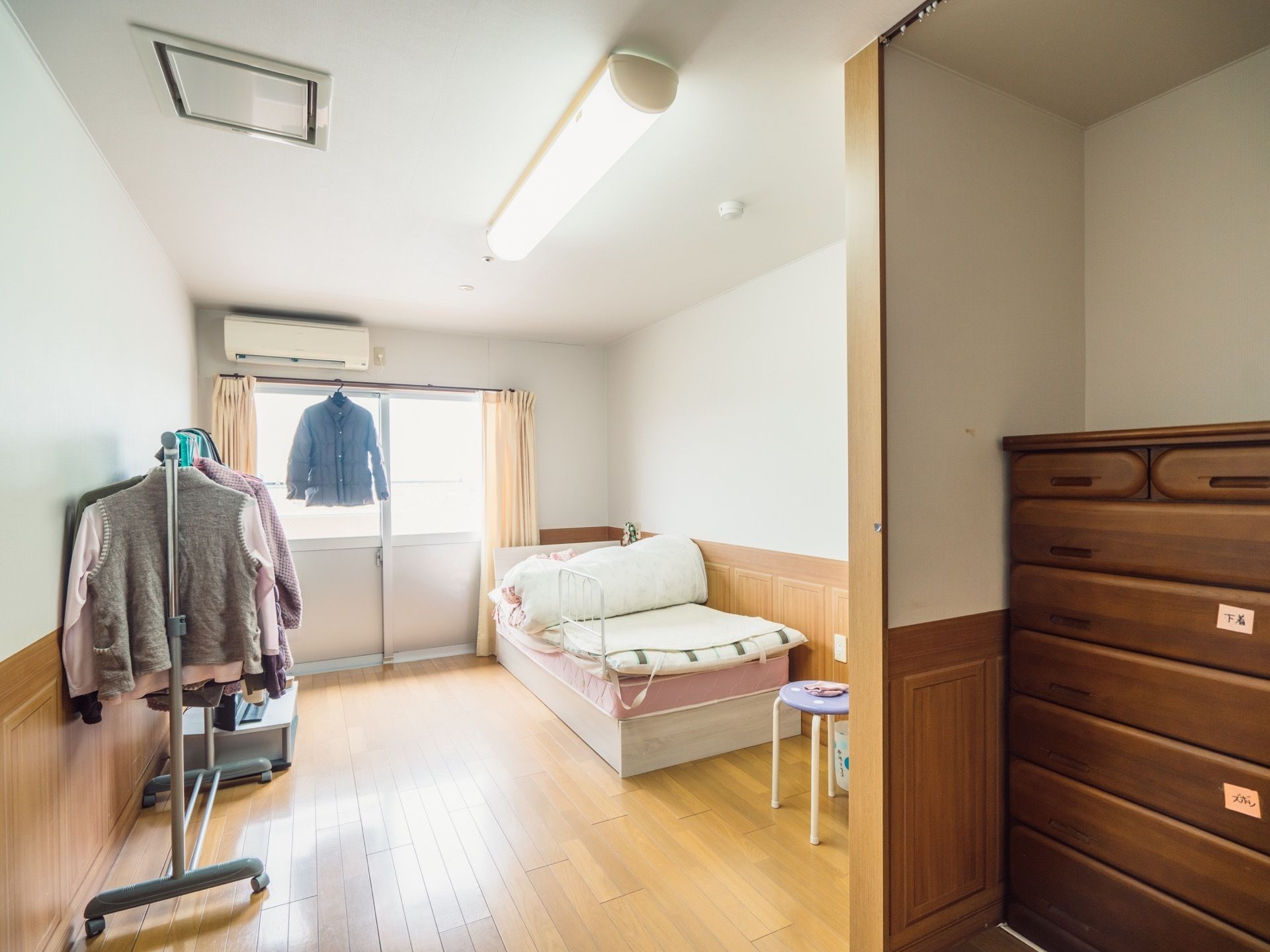 居室の窓は大きく、バルコニーに直接行くことができる。日当たりが良く、衣類をカーテンポールにかけて乾かすことができる。