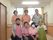 施設スタッフが廊下で写真にうつっている。6人のスタッフはピンクのポロシャツを着ており、1人は緑のエプロンをかけている。