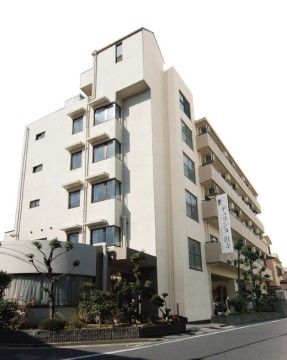 道路に面して建つ、ベージュの外壁で5階建てマンション型の施設