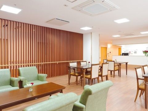 ロビーからのびた広い談話コーナー。テーブルと椅子がたくさんある。