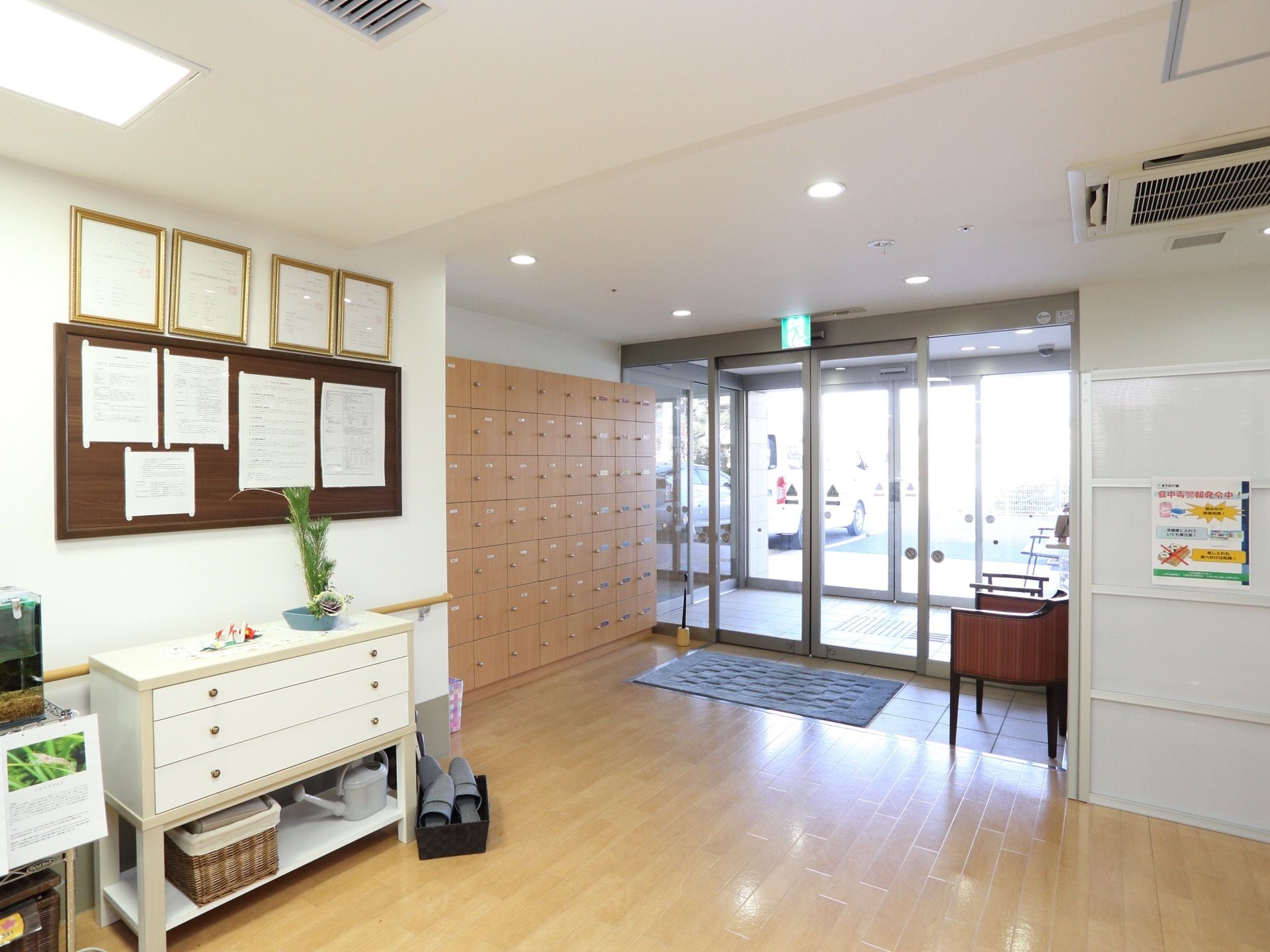 玄関は二重の自動ドアになっている。扉付きの下駄箱が設置されている。椅子が置かれていて、座れるようになっている。