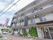 建物の左側は駐車場となっていて、軽自動車などが置かれている。その前には大きな看板があり、施設名が書かれている。