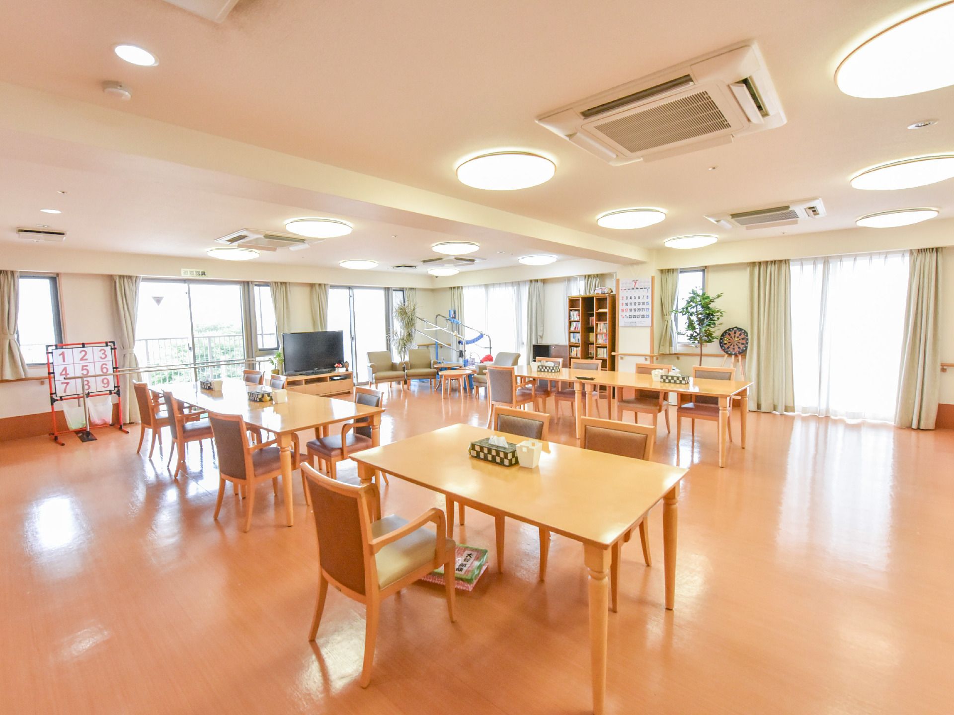 ダーツや的当ての遊具があり、大きな掃き出し窓から明るい光が差しこむ広い食堂