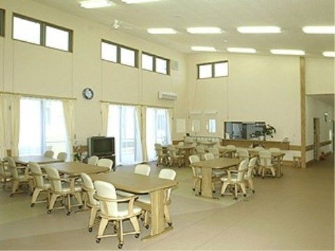 ベージュ色のテーブルとチェアが多く並ぶ、天井が吹き抜けの開放的な食堂