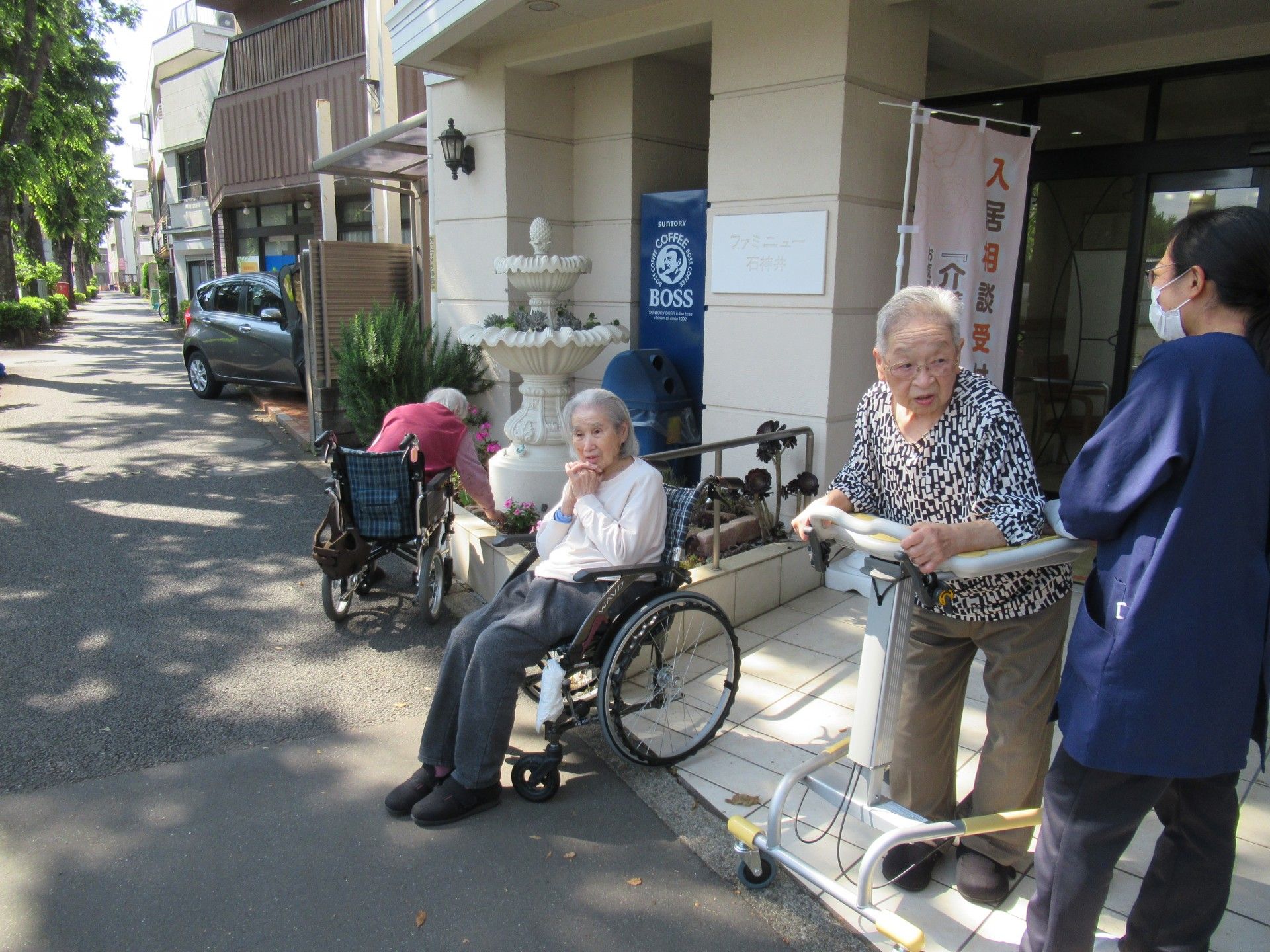 住宅街の中にあるレンガの広い道を楽しそうに進む、車椅子の男性とサポートする女性