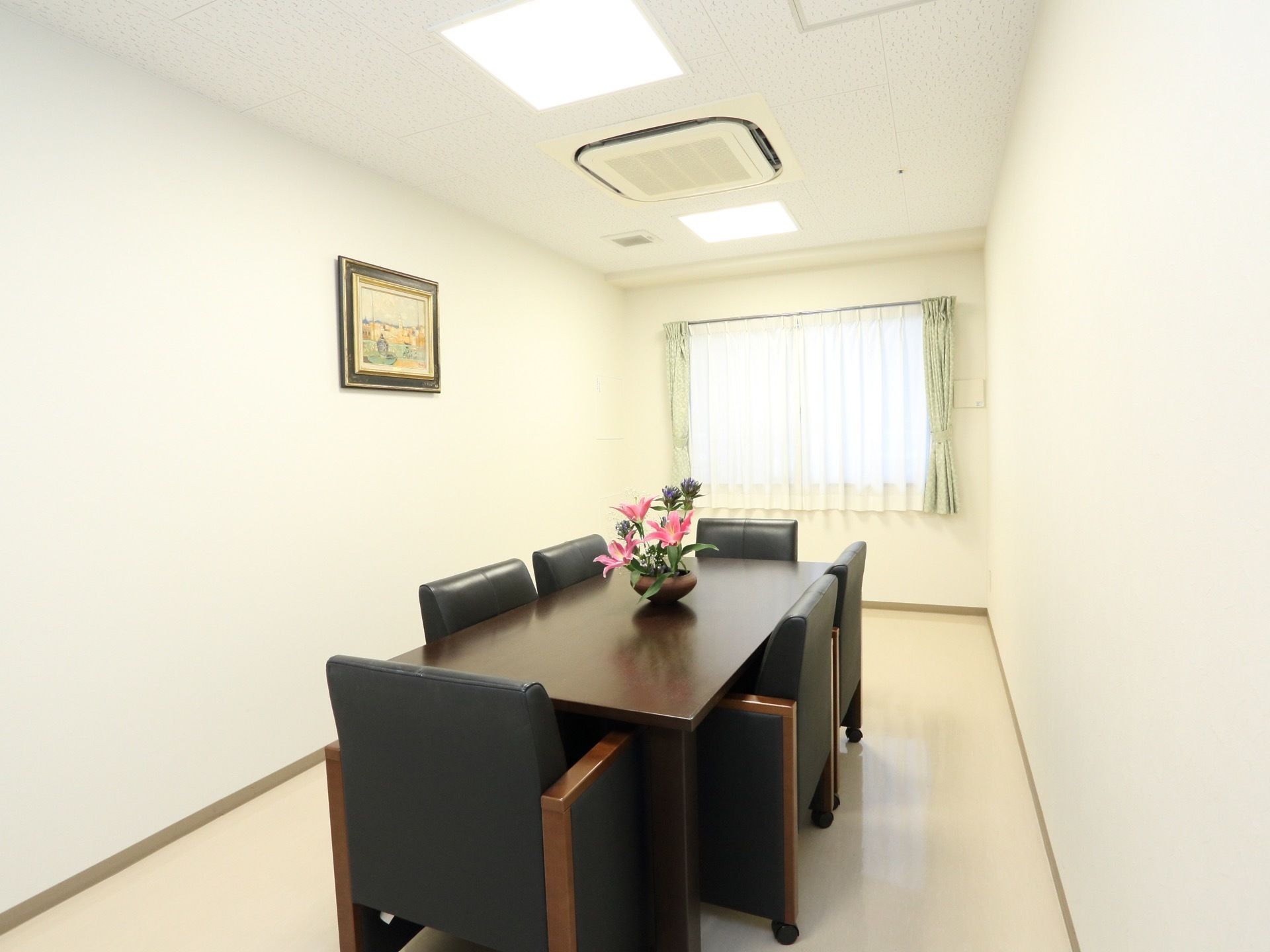 真っ白な清潔感のある相談室である。ゆったり座れるソファタイプのイスが６脚完備している。壁には絵画が飾られている。