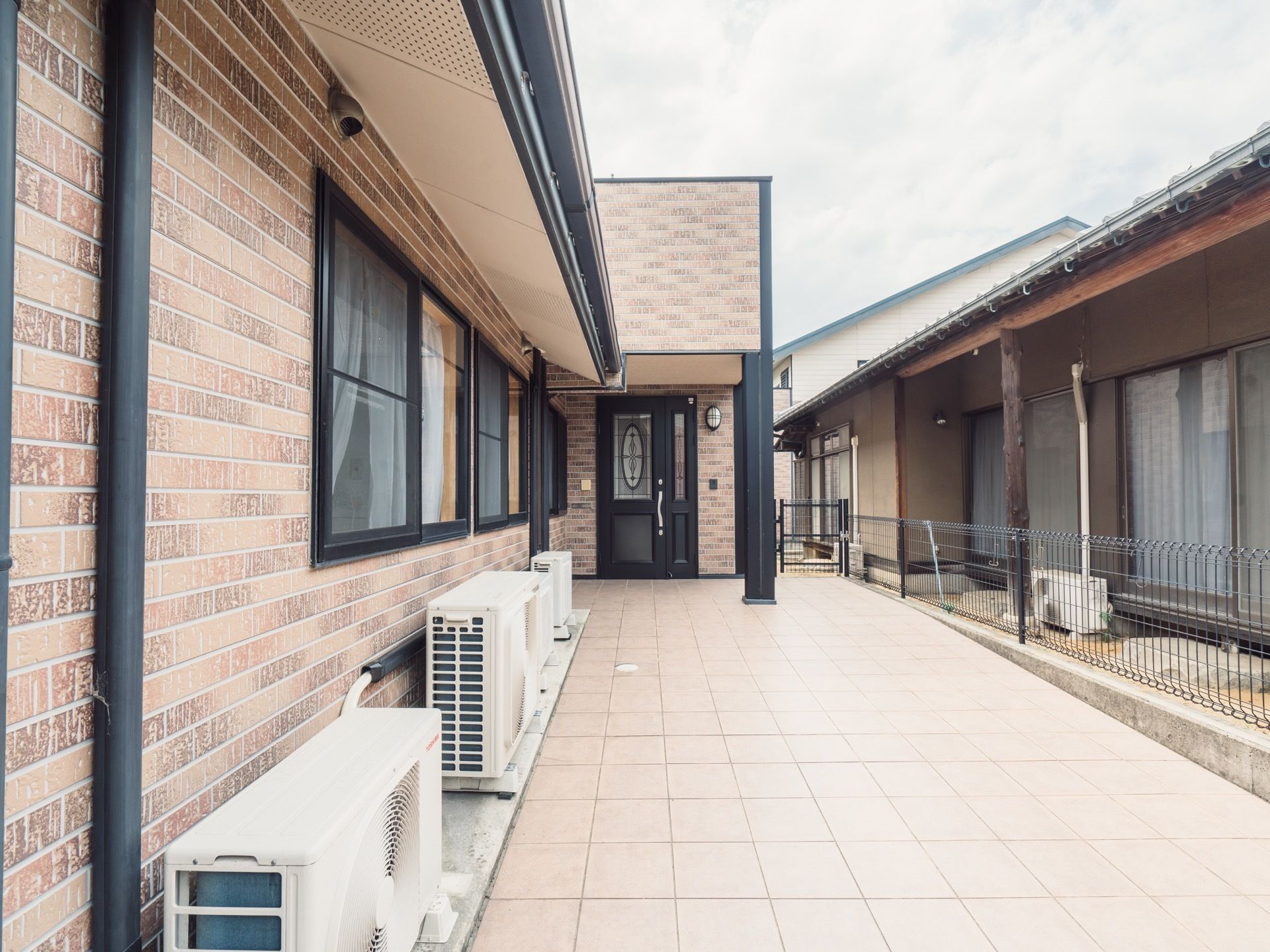 玄関は手前に引くタイプの扉になっている。大きな屋根があり、敷地の外に行く通路には段差がなくスムーズに行き来できる。