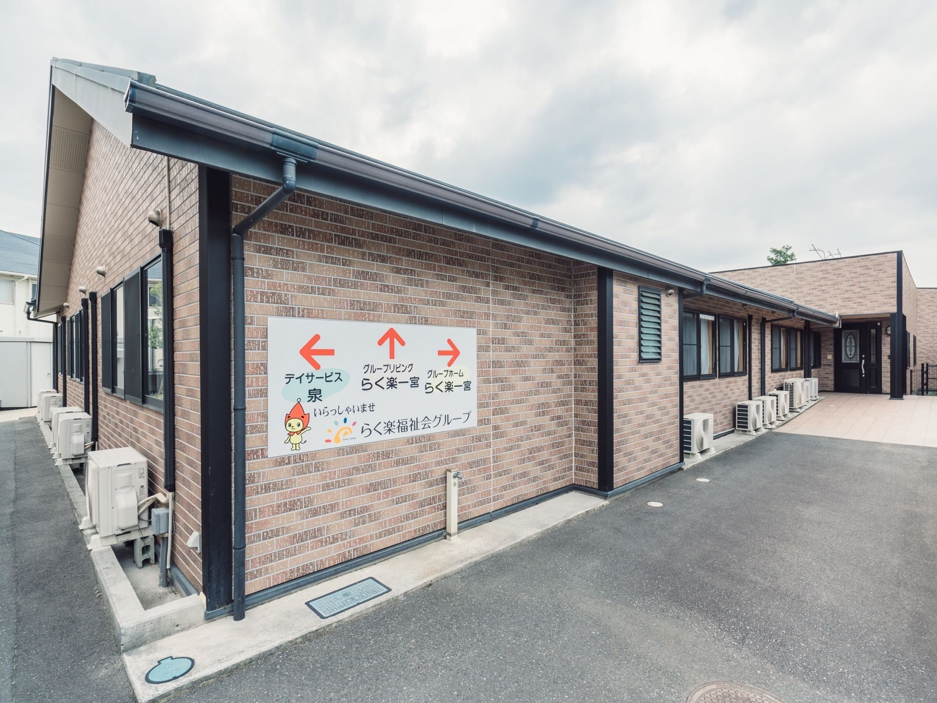 建物の壁に施設の看板がある。赤い帽子をかぶったキャラクターが描かれており、３つの施設の行く先を案内している。