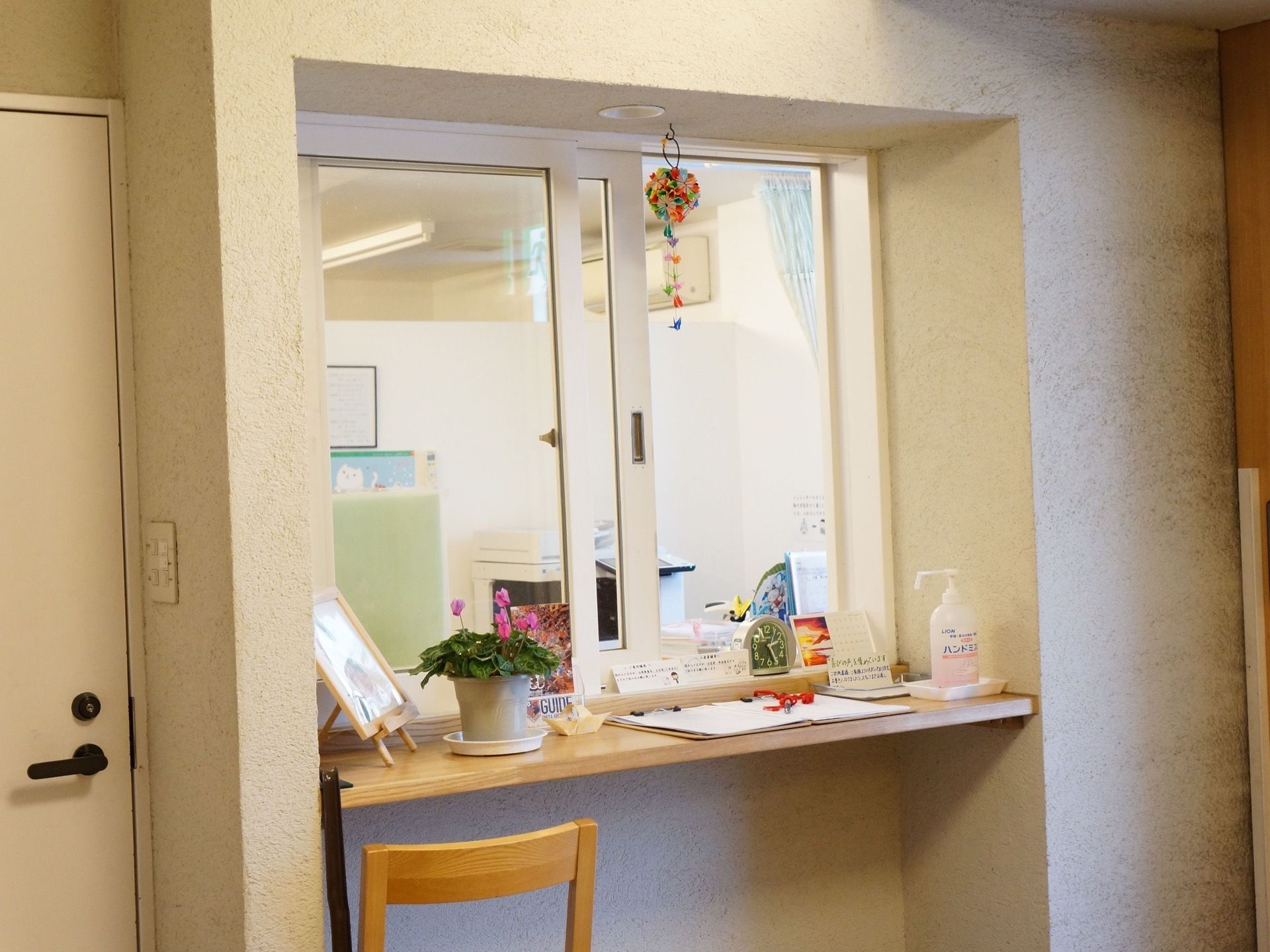 受付の窓には、折り紙で作られた毬が下げられている。カウンターの上には、小型の鉢植え・消毒薬などが置かれている。