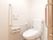 トイレは広く清潔感がある。扉はスライド式になっており安全に開閉することができる。壁にL字型に手すりが設置されている。