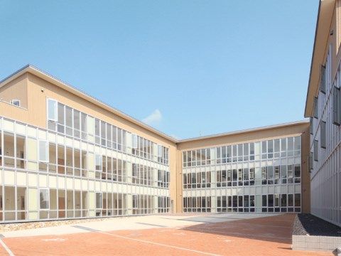 真ん中のスペースを囲むように建つ、3階建ての全面ガラス窓の建物