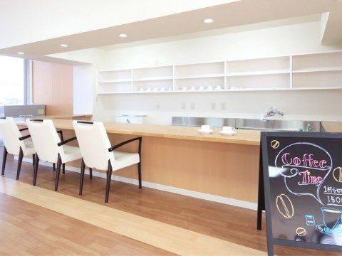 長い木製のカウンターと白い壁面、白いチェアでモダンな雰囲気のカフェスペース