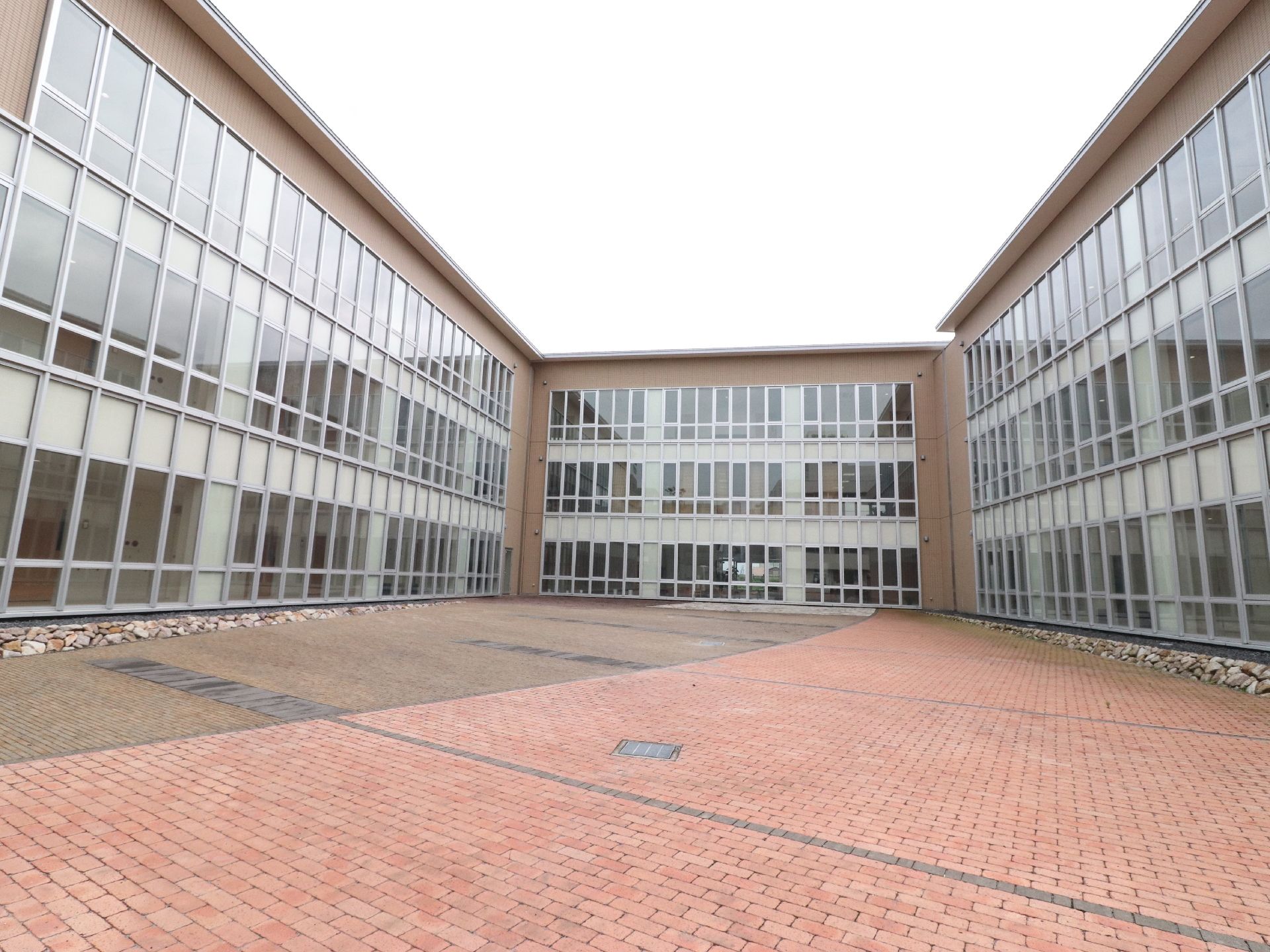 中庭から見た建物は、壁一面がガラス張りになっている。施設内には温かい日差しが入り明るい館内になっている。