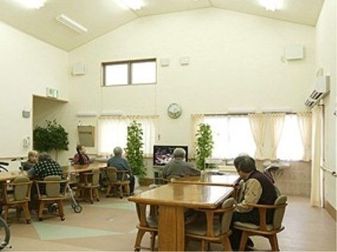 テーブルとキャスター付き椅子が多くセッティングされた、広く明るい吹き抜け天井の共有スペース