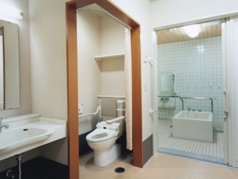 トイレと浴室がほぼ隣接して設置されている。ご使用時に立ち居が行いやすくなるよう、肘置きや手すりを取り付けている。