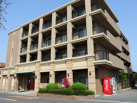 ２車線の公道に面した舗装された敷地に建つ、鉄骨造り地上４階建ての建物