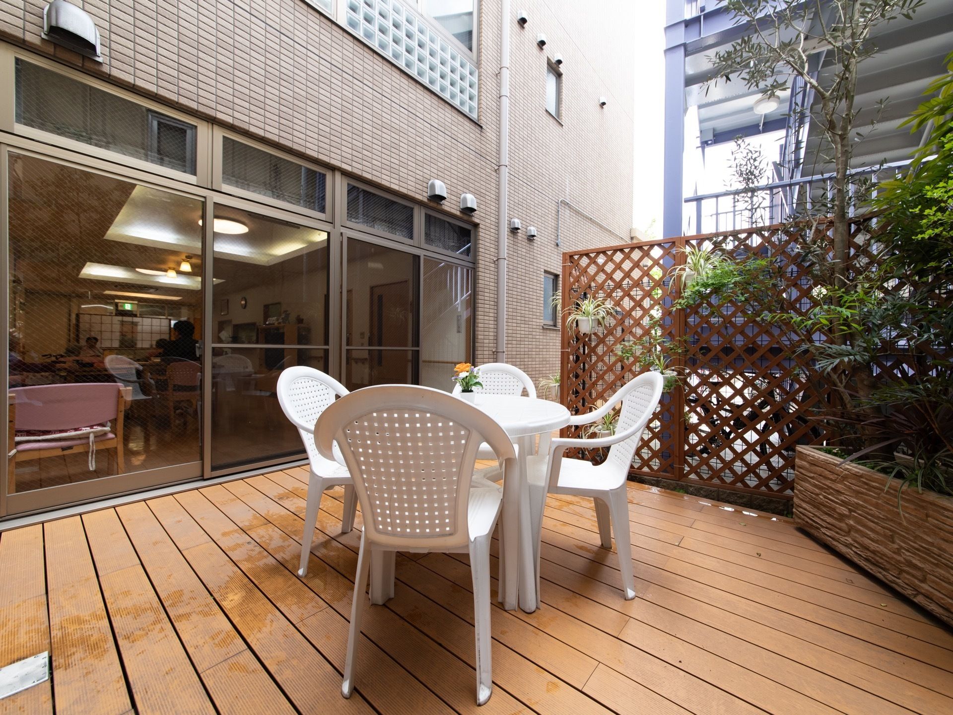 バルコニーと共有スペースの間には段差がなく、間口の広いドアから車椅子でも気軽に外に出ることができる。白のテーブルセットが中央に置かれている。