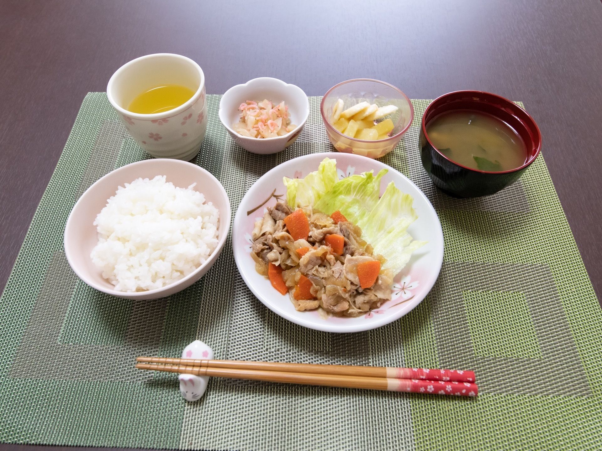ある日の食事メニューは、ご飯に野菜と肉の炒め物、汁物、小鉢、フルーツ、お茶といった内容。一品ごとにお皿にきれいに盛り付けられている。