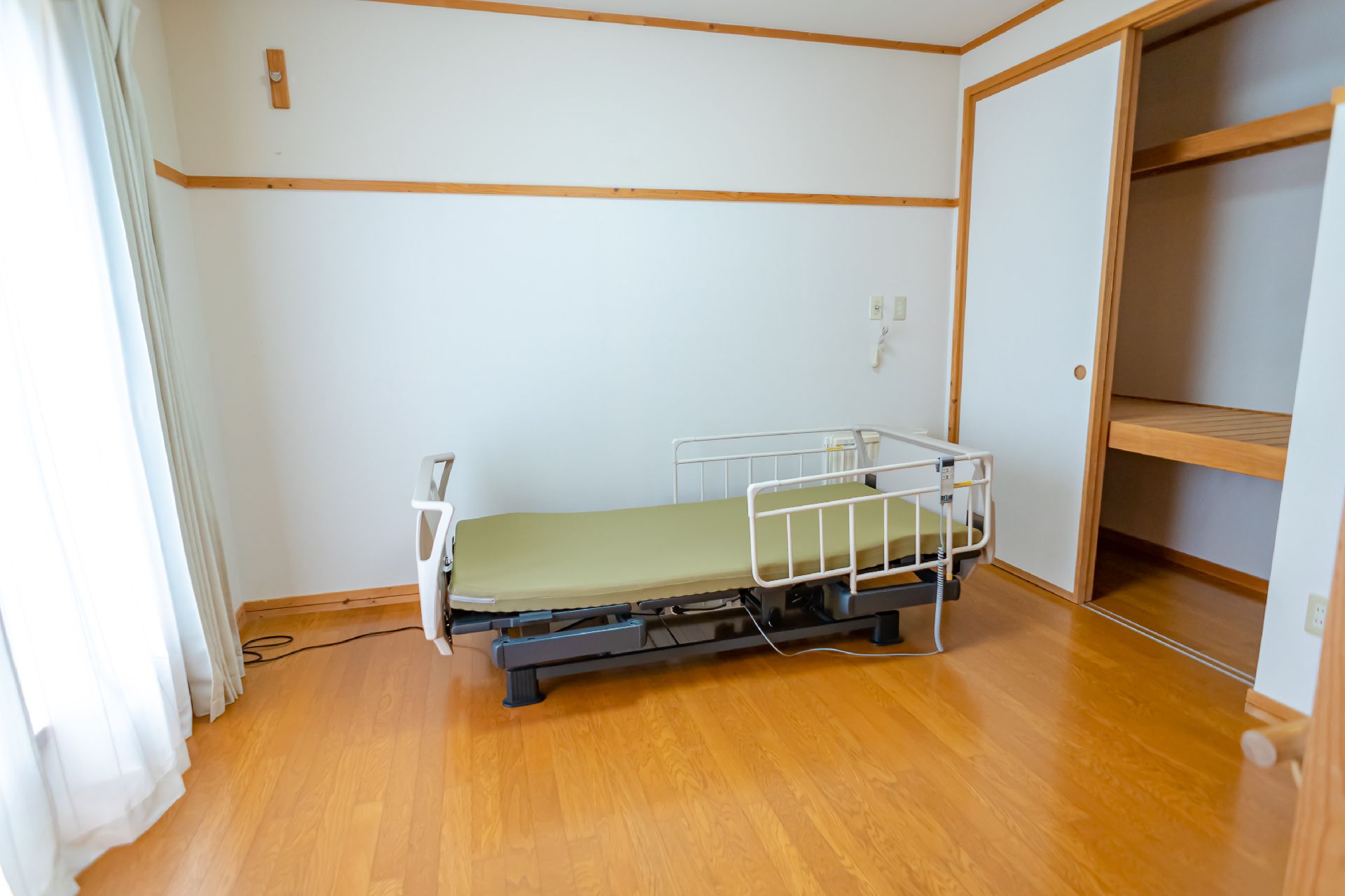 緑のマットが敷かれたベッドが配置された白い壁の部屋