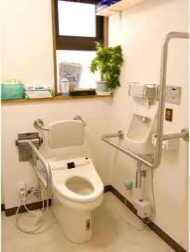 洋式トイレには背当てや可動式の手すりが設置されており、車椅子をご利用の方にも使いやすい。壁にもしっかりとした手すりが備わっている。