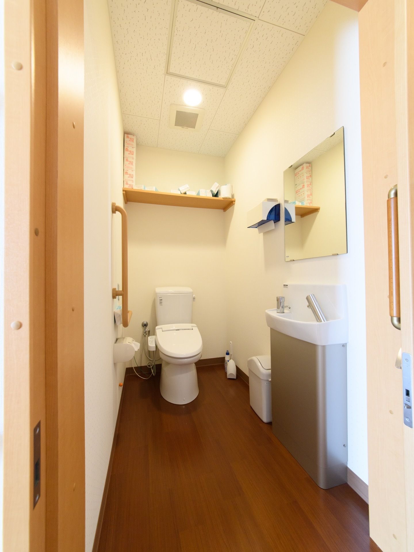 奥行きのある広い室内である。壁際に洗面台と鏡とハンドペーパーが設置されている。床にはゴミ箱が置いてある。