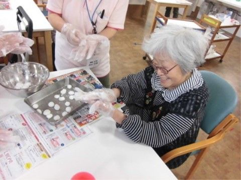 ポリエチレン製の手袋をはめて白い団子を丸める作業を行っている人々