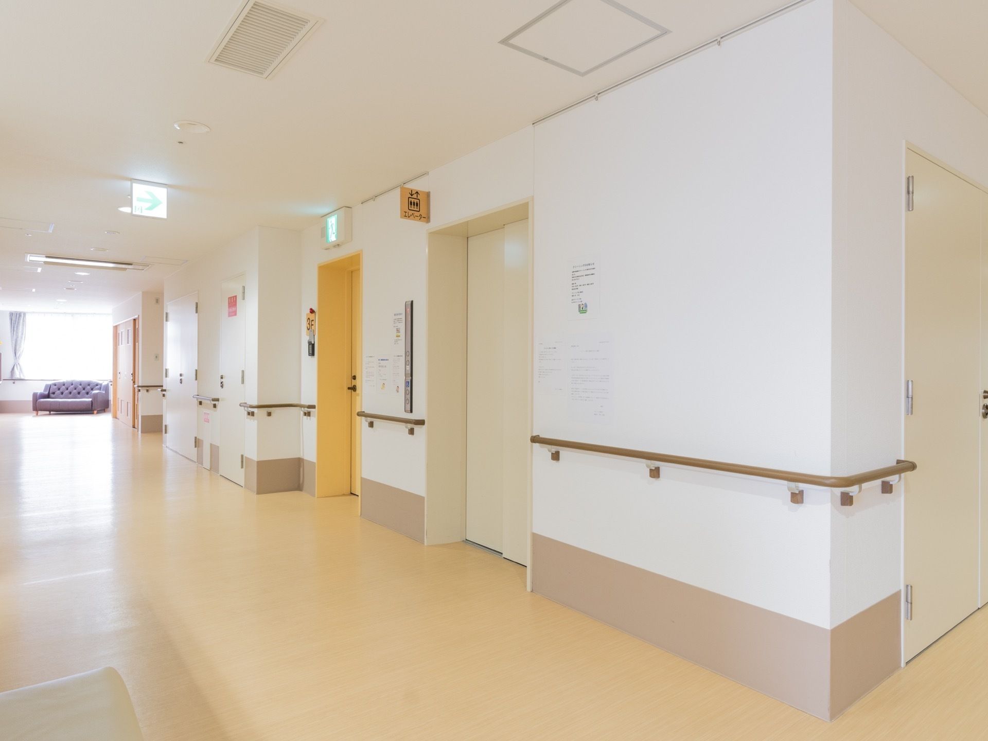 通路は広々としている。壁には手すりが取り付けられている。エレベーターの近くの壁には表示パネルがある。