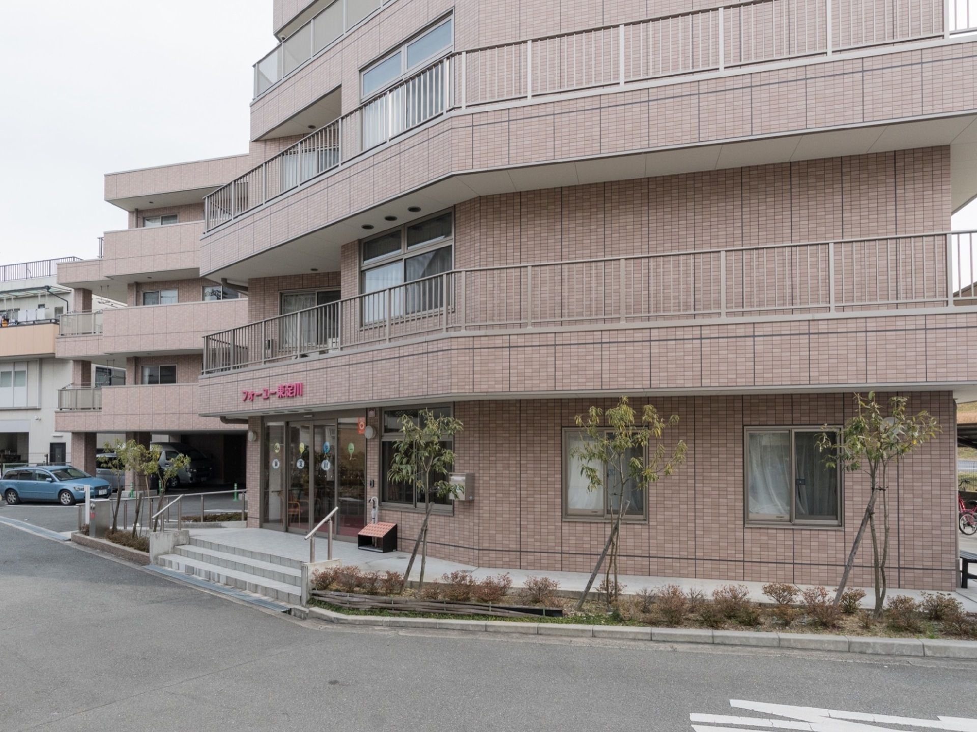 施設の周りには植え込みがある。道路に面した場所から見える位置の2階から4階までの通路には柵が取り付けられている。